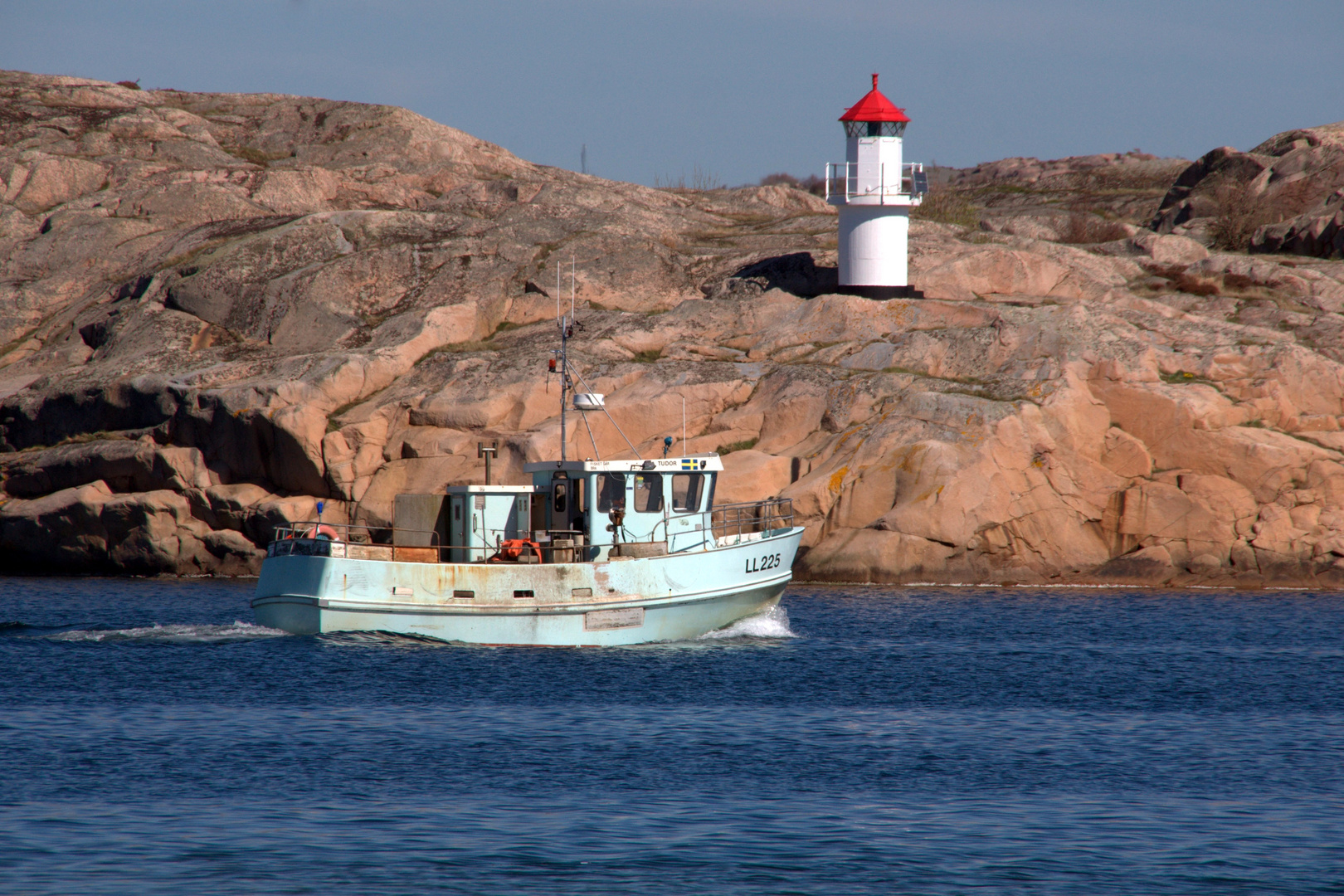 Fischerboot vor kleinem Leuchtturm