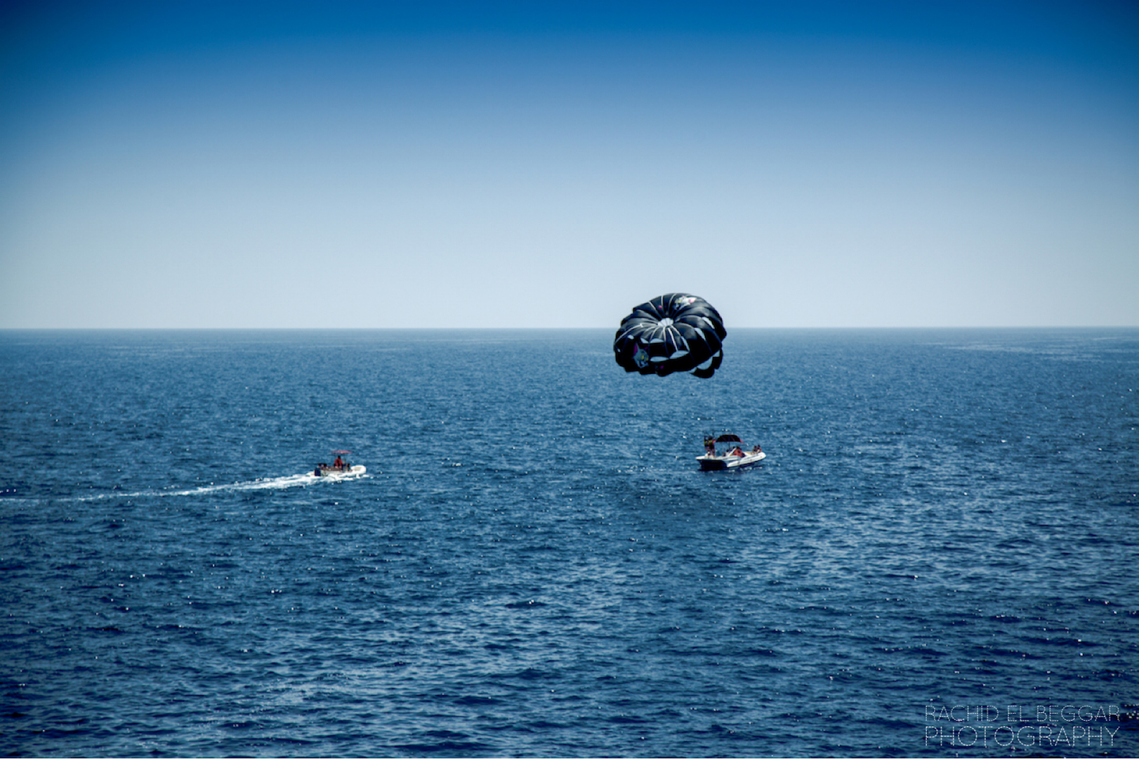 Fliegen an einem Fallschirm hinter einem Boot auf einen Urlaub am Meer 