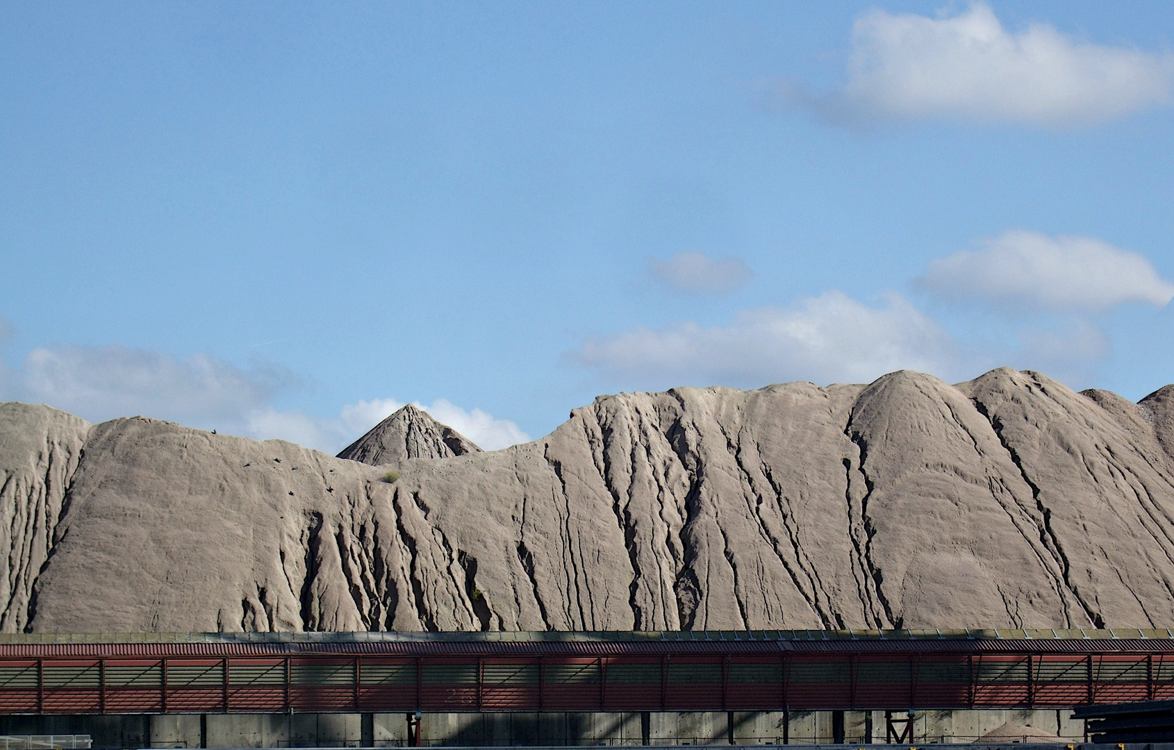 Förderbandanlage (?) vor einem Kohlegebirge.