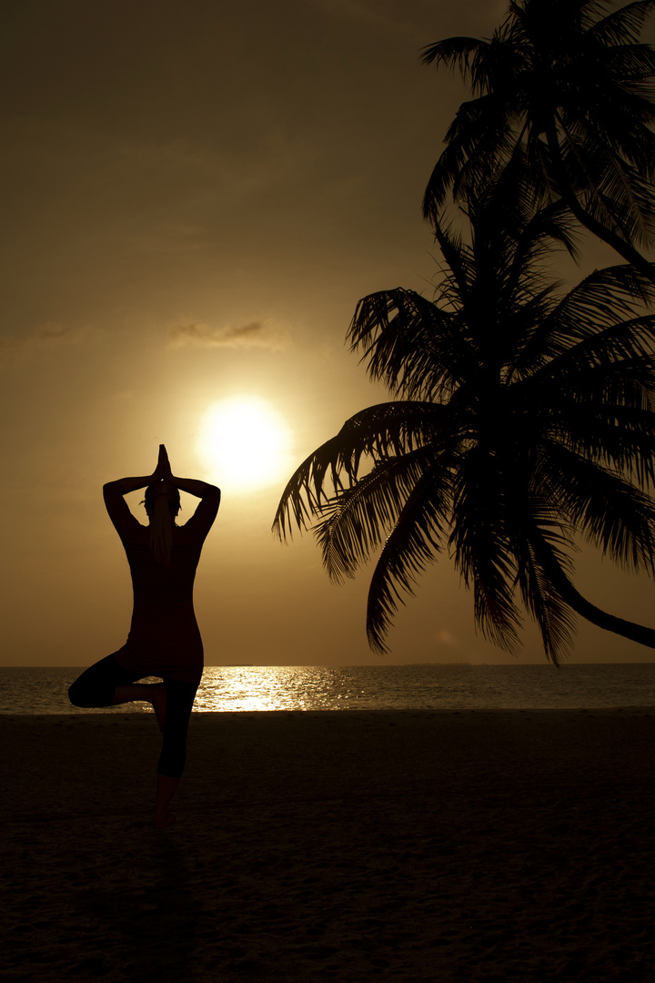 Frau macht Yoga am Strand