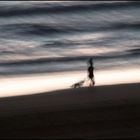 Frau mit Hund abends am Meer