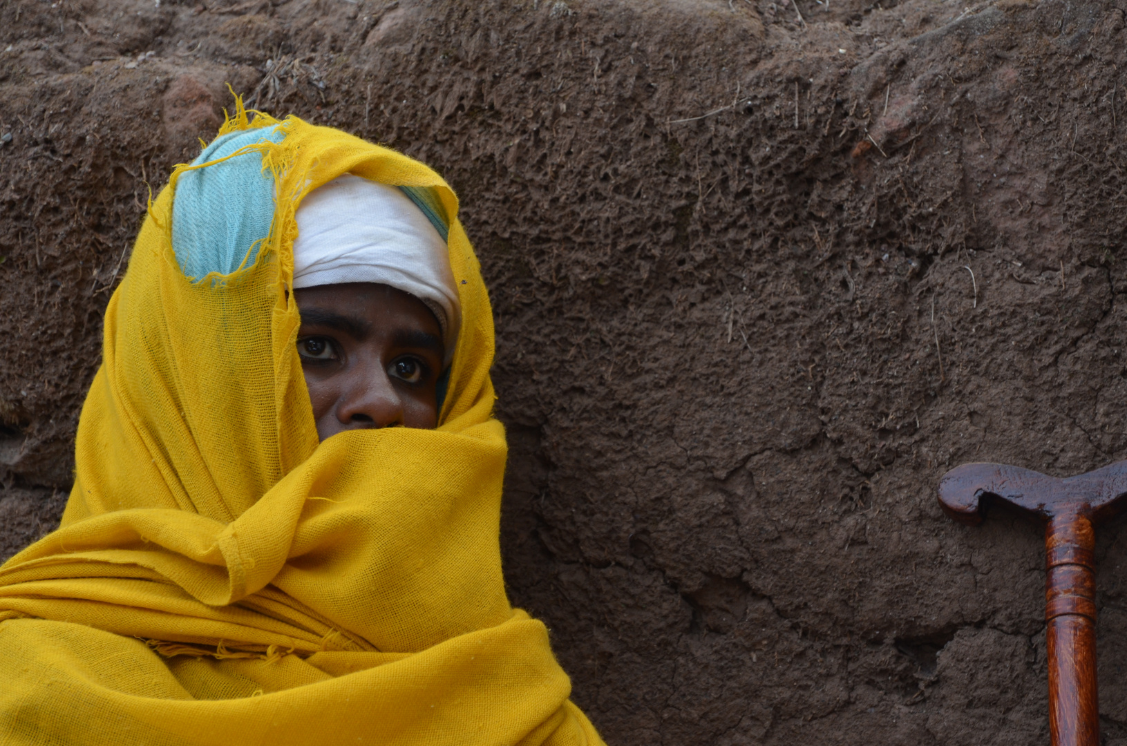 Frau neben einem Gebetsstock vor der Erlöserkirche in Lalibela