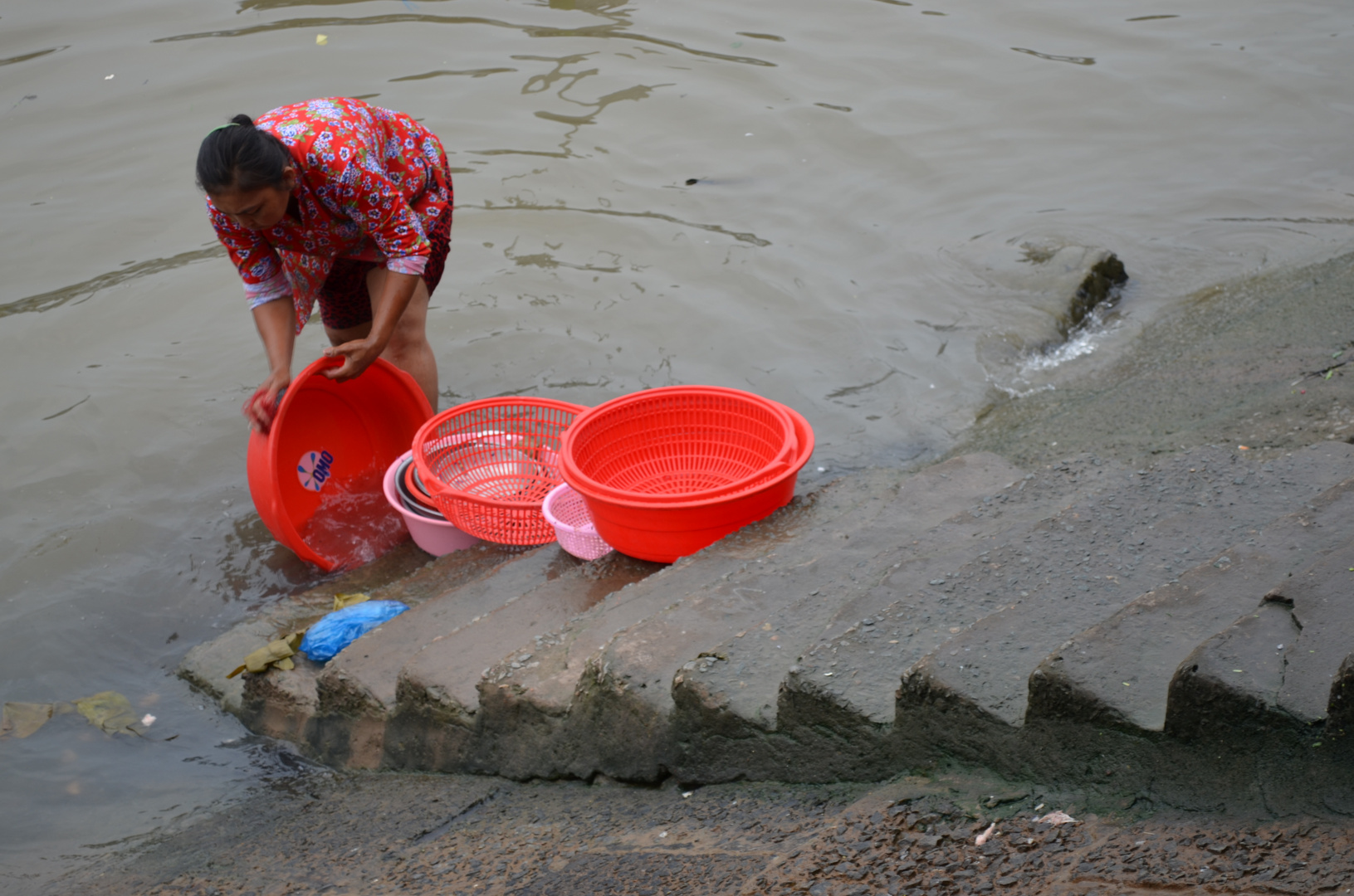 Frau wäscht Schüsseln im Mekong (Südvietnam)