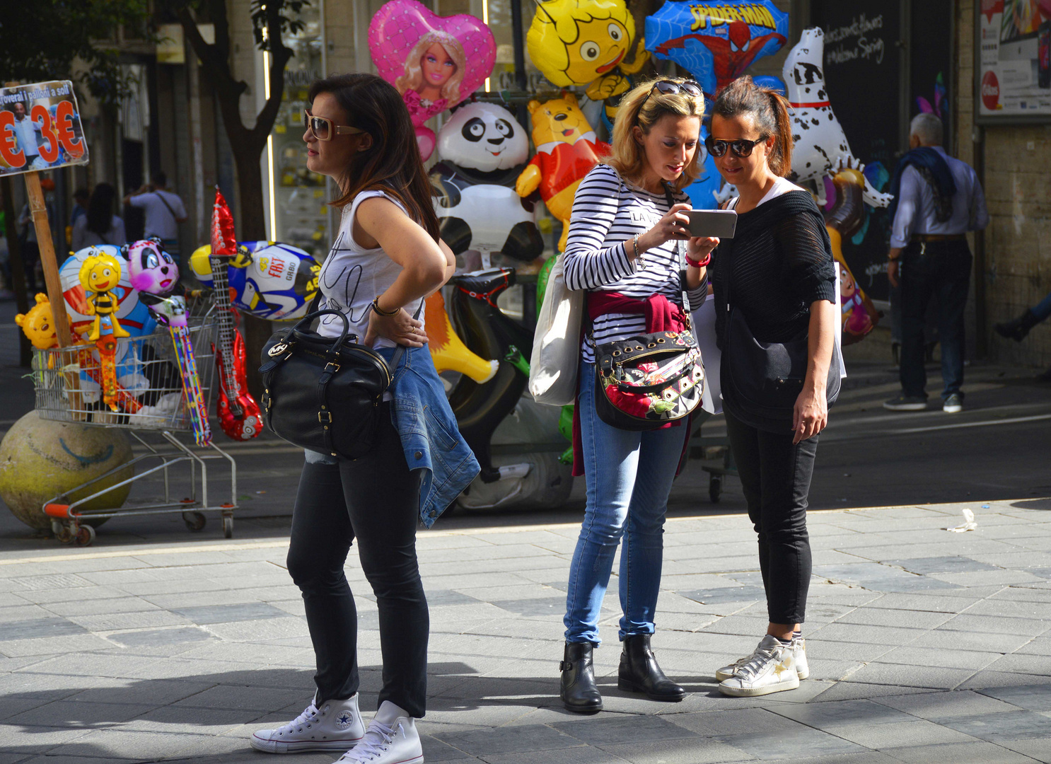 Frauen am Handy vor Spielzeugballons in der farbenfrohen Fußgängerzone von  Neapel