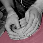 Frauenhände töpfern eine Tonschale auf einer Töpferscheibe