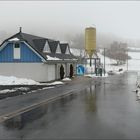 Garagenhaus und kleiner Silo in nieseliger Schneelandschaft