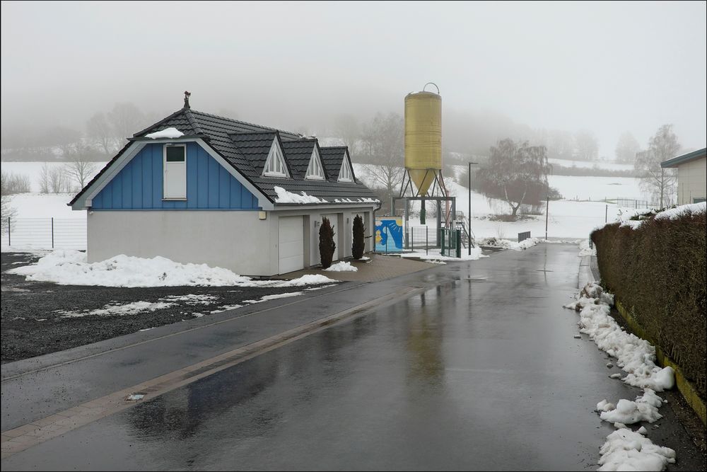 Garagenhaus und kleiner Silo in nieseliger Schneelandschaft