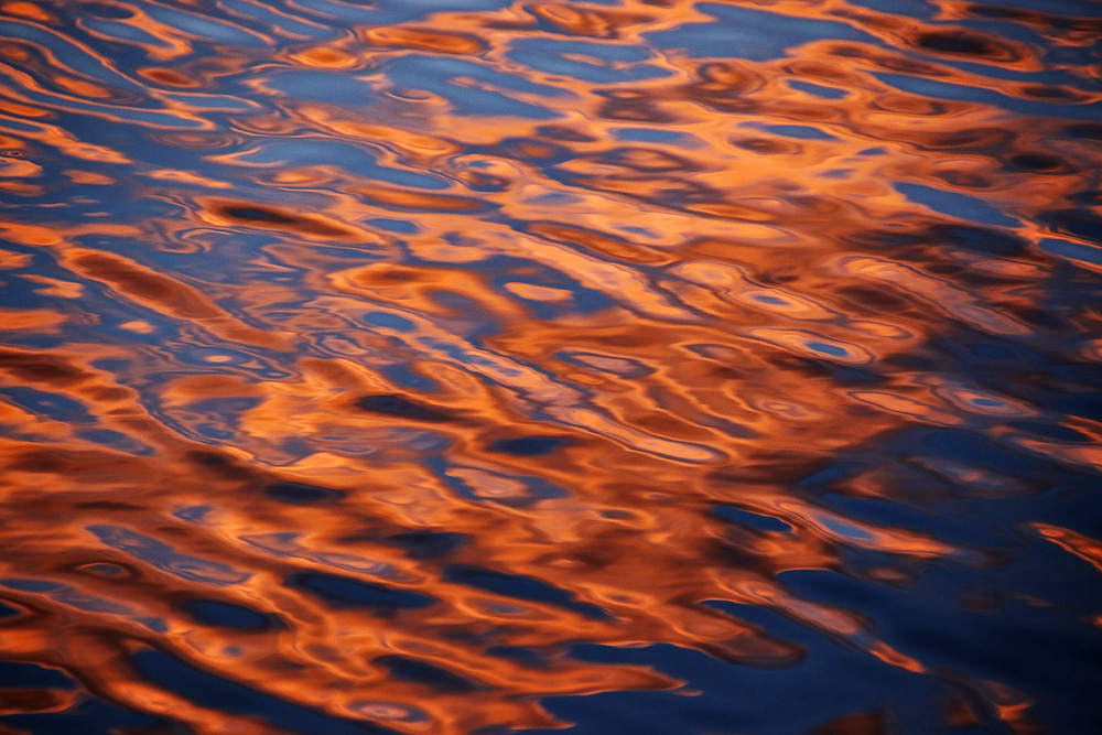 gefärbe Wolken spiegeln sich auf der Wasseroberfläche