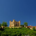 Gelbe Burg auf grünem Berg vor blauem Himmel