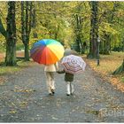 "Gemeinsamer Weg" - Mutter und Sohn beim Spaziergang mit bunten Regenschirmen im Herbst im Park