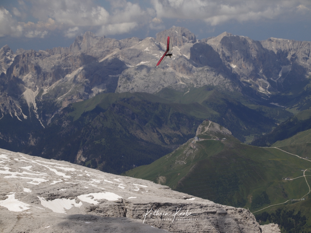 Genussvoller Flug eines Drachenfliegers am Piz Boe mit Blick zur Bergstation des Sass Pordoi