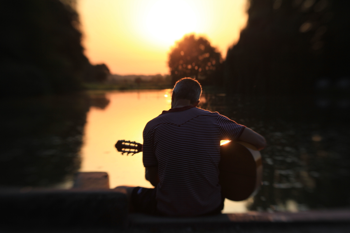 Gitarrenspieler bei Sonnenuntergang am See