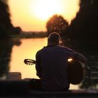 Gitarrenspieler bei Sonnenuntergang am See