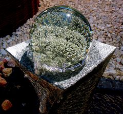 Glaskugel auf einem Steinbrunnen vom Wasser getragen und bewegt