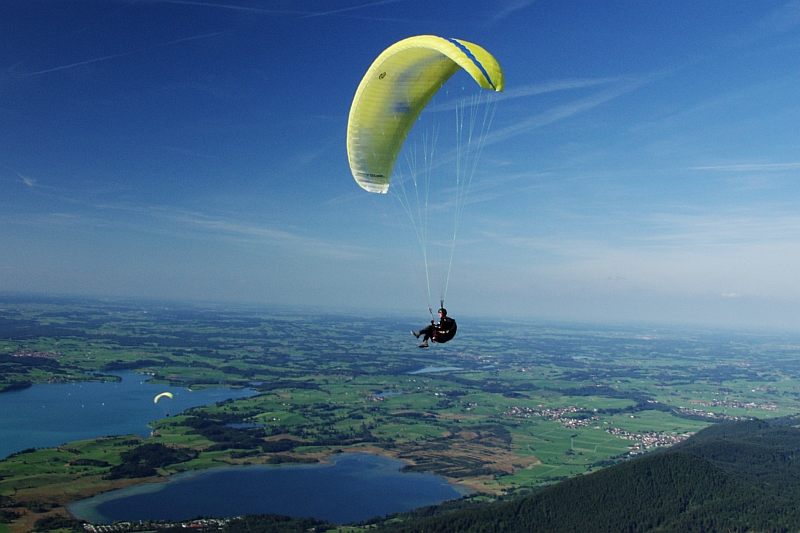 Gleitschirmflieger am Tegelberg mit Bannwaldsee Forggensee und Lechtal