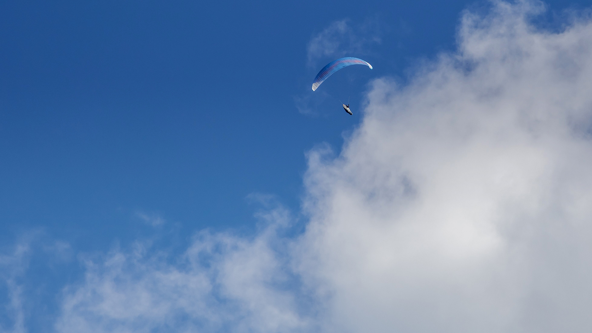 Gleitschirmflug unter blauem Himmel