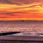 Goldener Sonnenuntergang mit Frachtschiff und Windrädern vor der Küste von Cadzand (Holland).