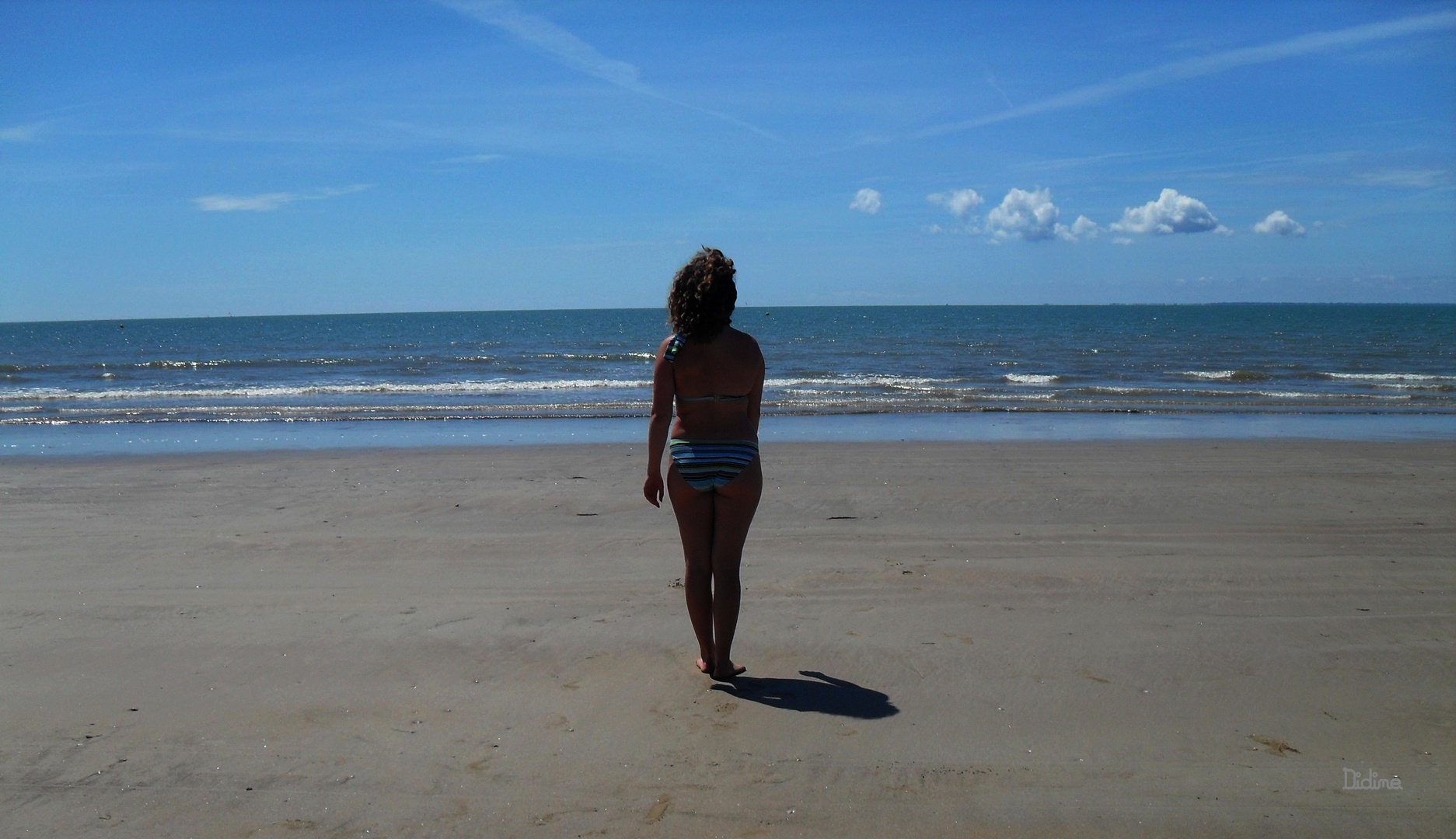 Grains de sable dans les cheveux, mer devant les yeux.