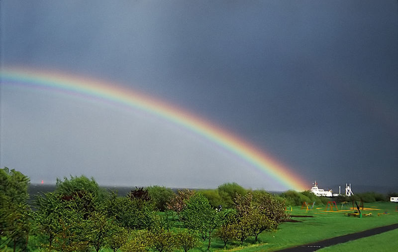 Grünendeich mit Barkasse und Regenbogen.