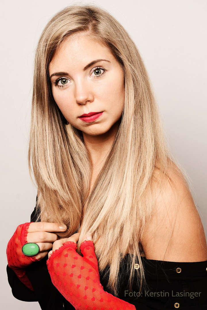 Grüner Ring und rote Handschuhe (an blonder Frau)