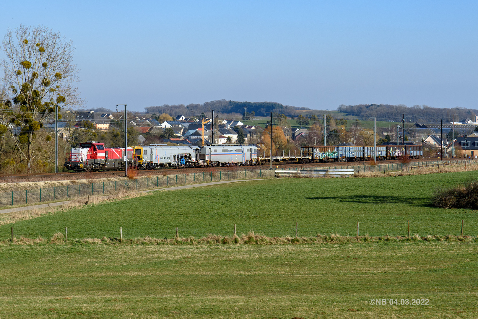 Güterzug mit Gleisbaumaschinenüberfahrt