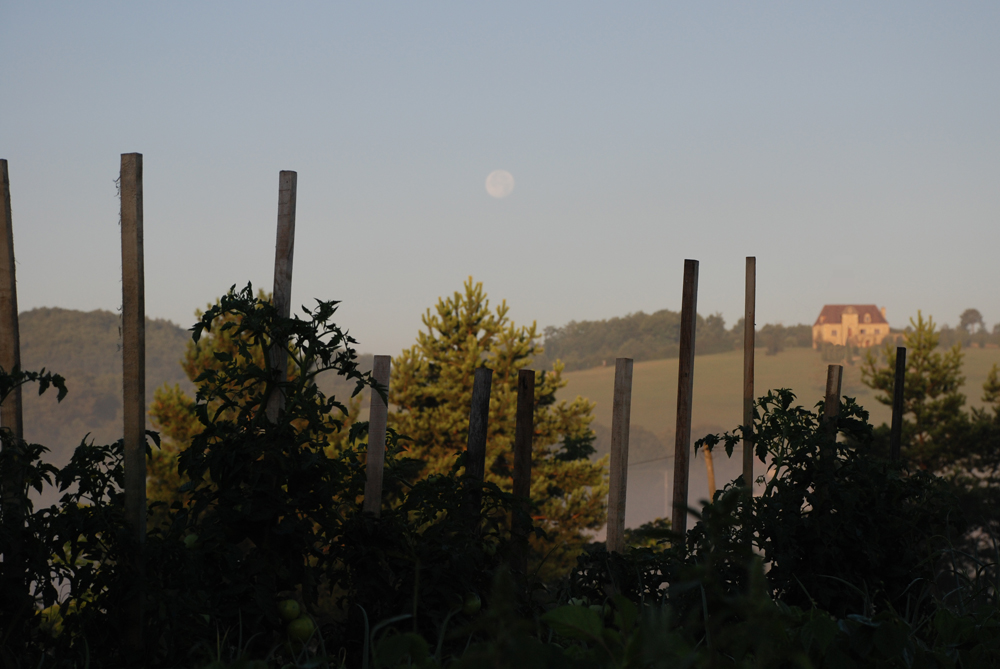 Haus bei untergehendem Mond und aufgehender Sonne.