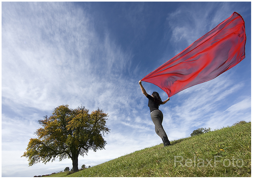 "Herbstwind" - Junge Frau mit wehendem rotem Tuch vor blauem Himmel