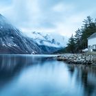 Hütte am Fjord mit Wolken in den Bergen