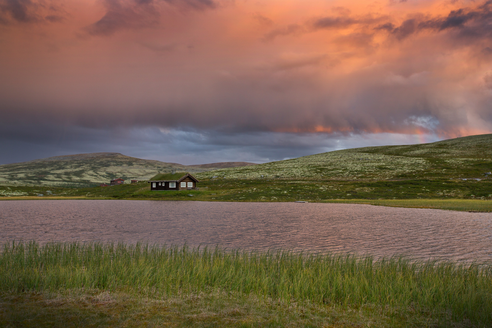 Hütten mit See in Landschaft von Norwegen im Sonnenuntergang