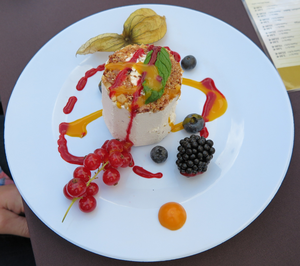 Ice cream with decoration of fruits, nut slivers, mint, and a potpourri of sauces