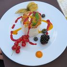 Ice cream with decoration of fruits, nut slivers, mint, and a potpourri of sauces