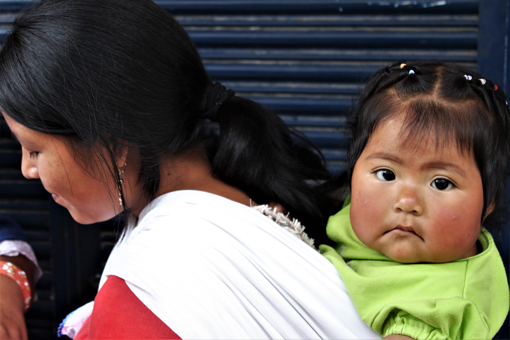 indigenes Mädchen auf dem Rücken der Mutter in Otavalo