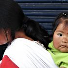 indigenes Mädchen auf dem Rücken der Mutter in Otavalo