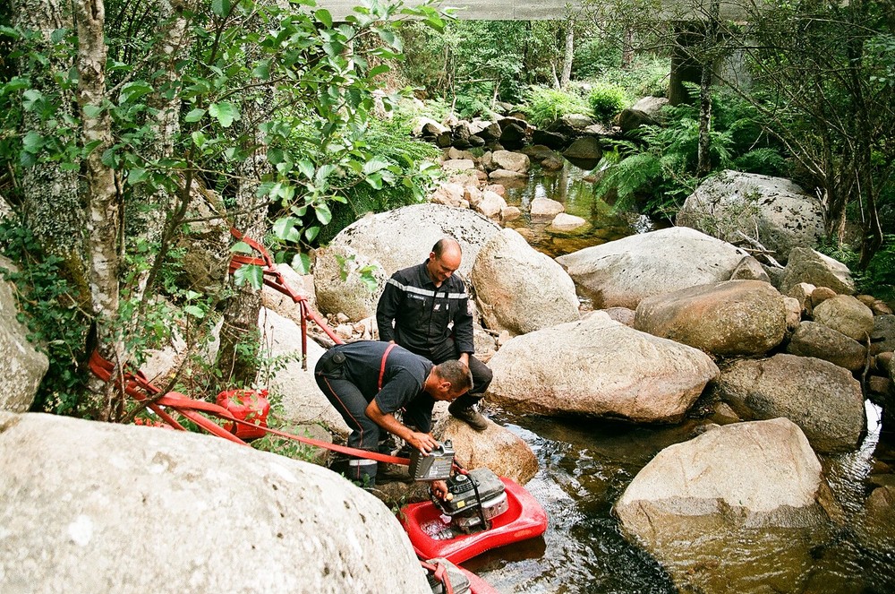 Installation d’une motopompe dans une rivière pour le ravitaillement des camions.