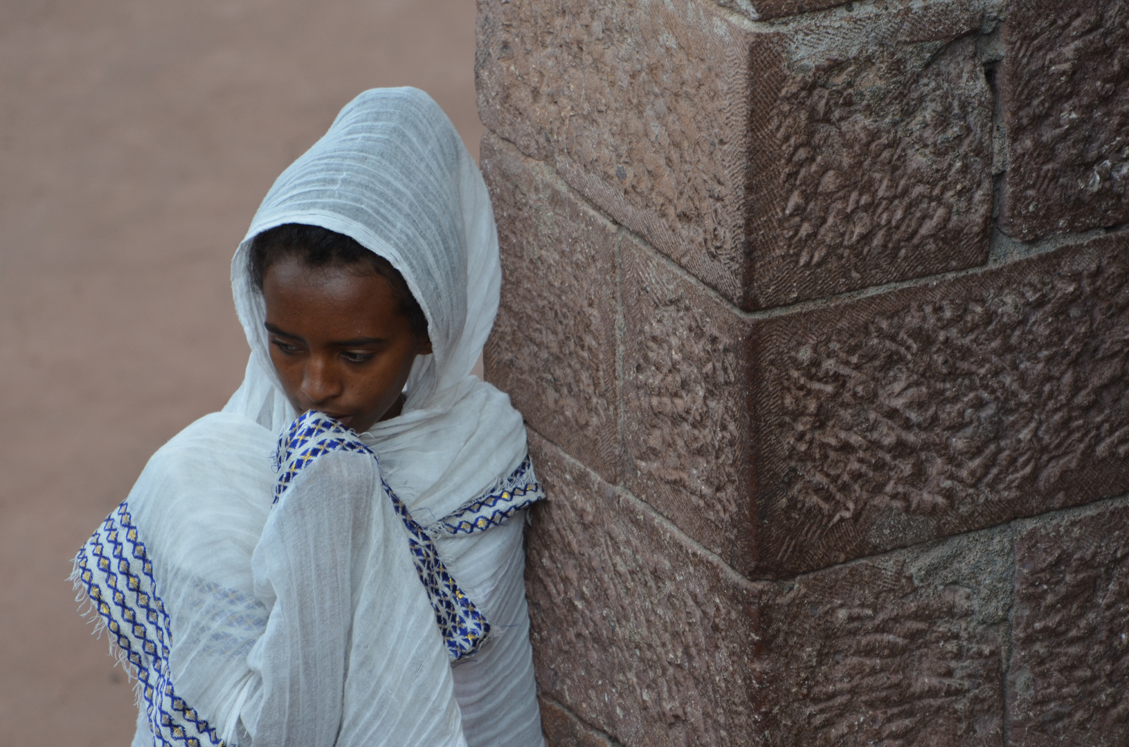 Junge Frau an einer Mauer in Lalibela (Erste Kirchengruppe). 