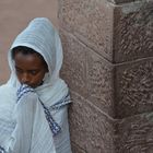 Junge Frau an einer Mauer in Lalibela (Erste Kirchengruppe). 