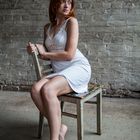 Junge Frau im weißen Kleid, auf einem Stuhl sitzend