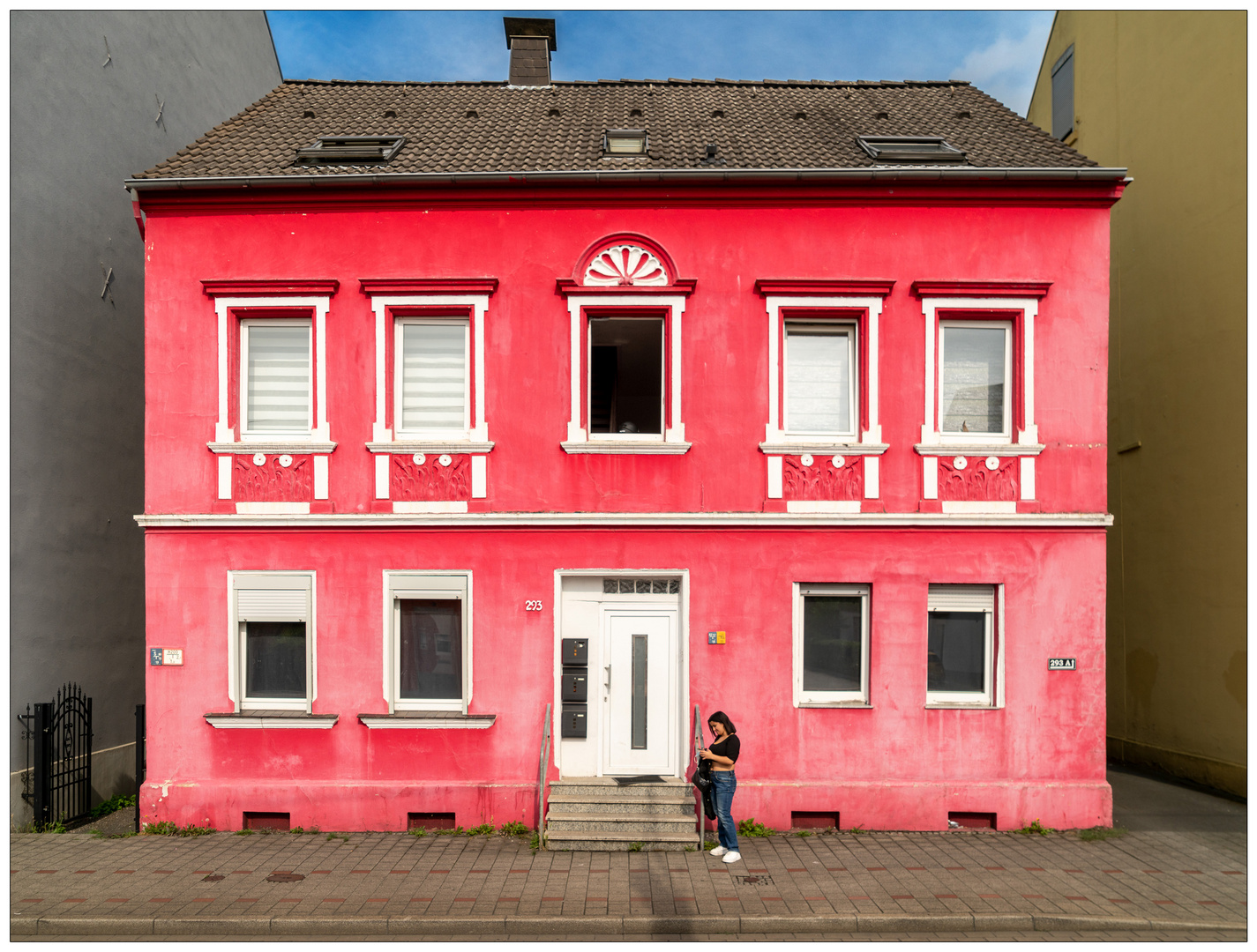 Junge Frau mit Smartphone vor rosa Fassade