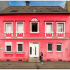 Junge Frau mit Smartphone vor rosa Fassade