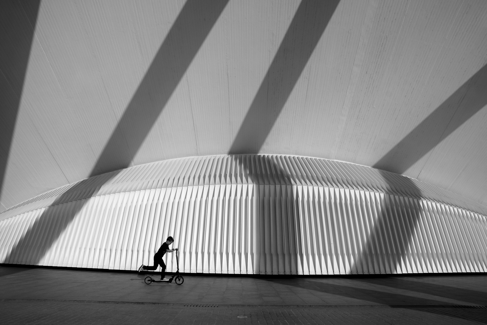 Junge mit Roller vor Schattenlinien und Gitterstruktur