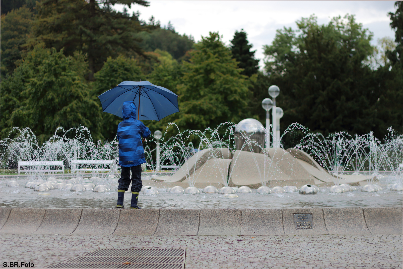 Junge spielt am Brunnen