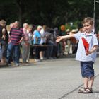 Junge wartet bei Marathon auf Abklatschen der Läufer