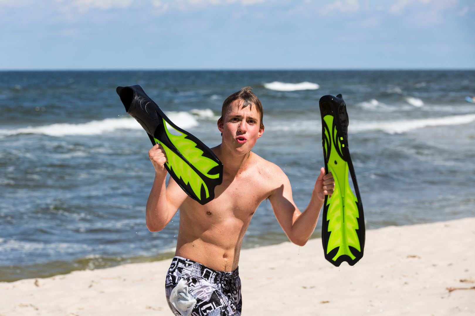 junger Mann mit Flossen am Strand