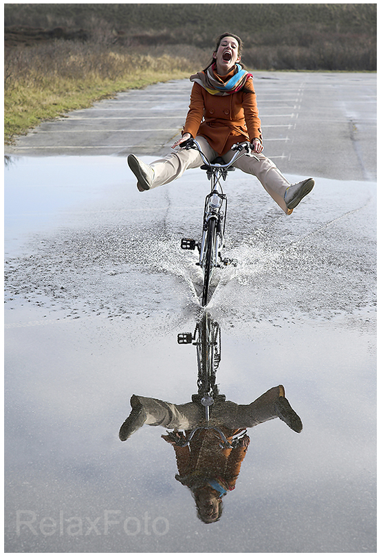 "Just for fun" - Junge Frau fährt begeistert mit Fahrrad durch Pfütze