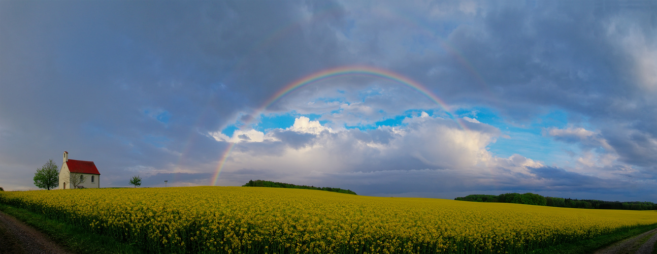 Kapelle und Regenbogen über einem Rapsfeld