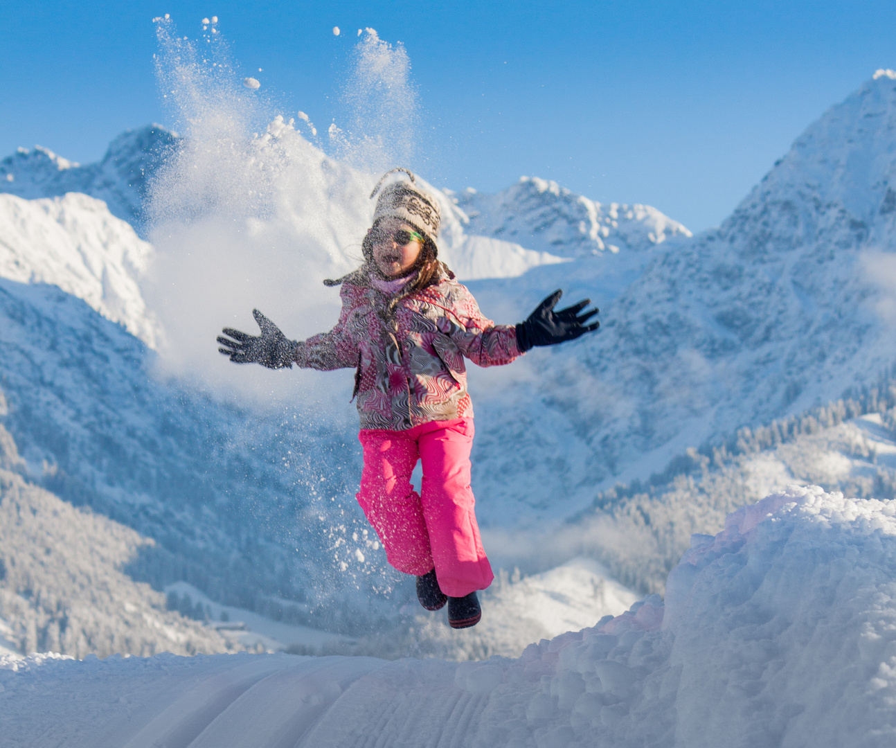 Kind im Schnee vor Alpenpanorama