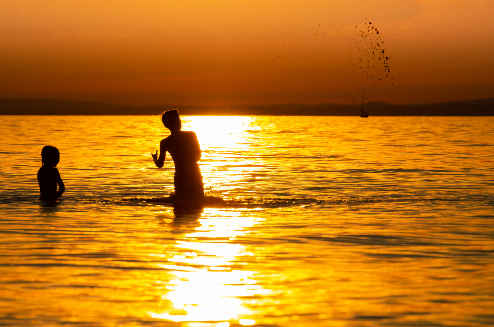 Kinder im Wasser bei Sonnenuntergang