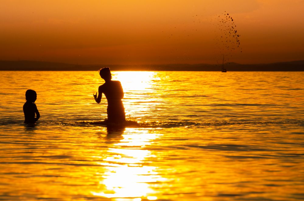 Kinder im Wasser bei Sonnenuntergang