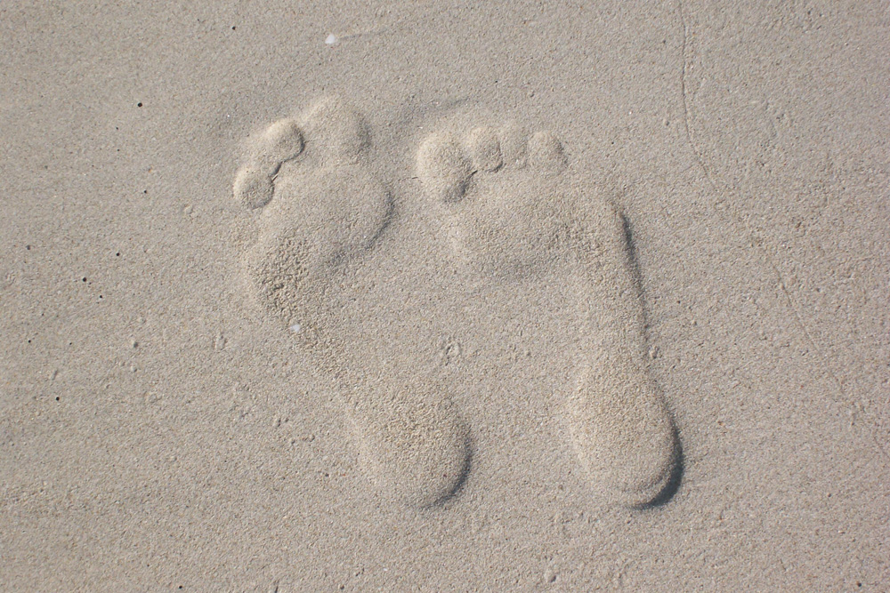 Kippbild Fußabdrücke im Sand