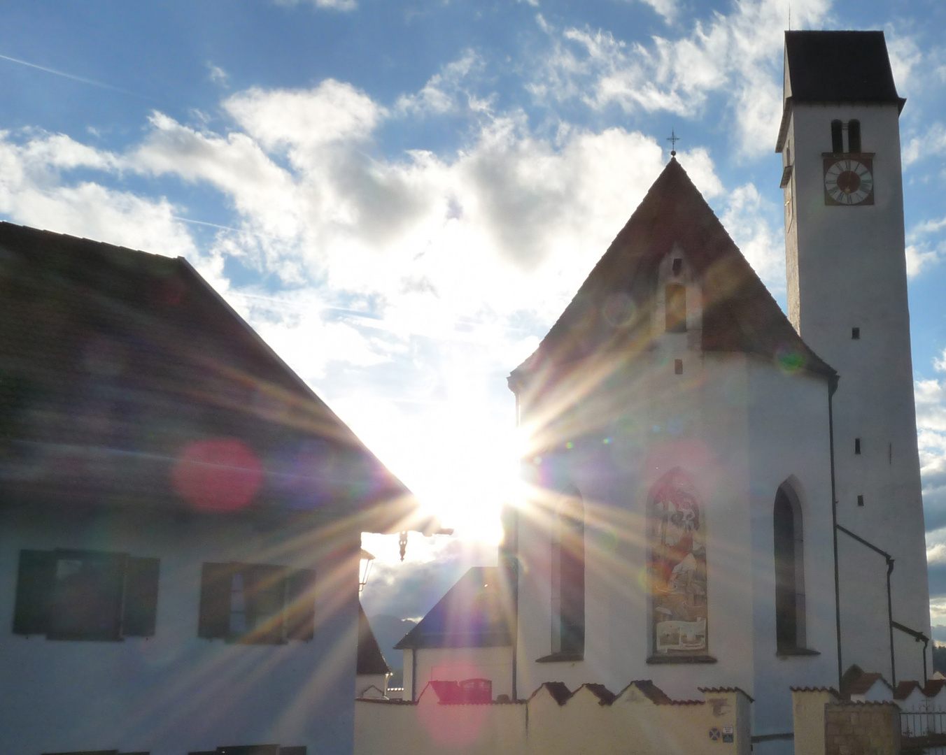 Kirche und Haus mit Sonne dazwischen